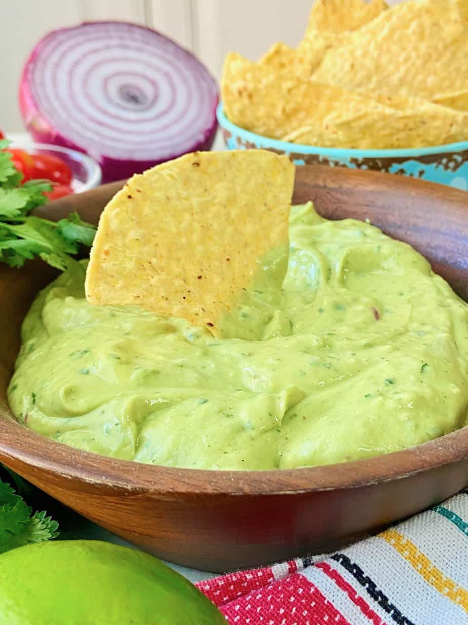 Yellow corn tortilla chip in avocado dip.