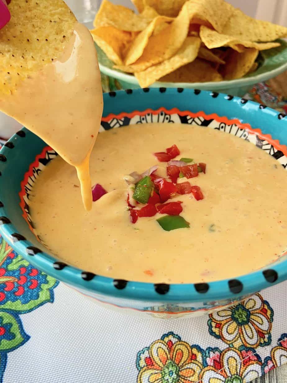 Tex-Mex Chile con queso dripping off a tortilla chip.