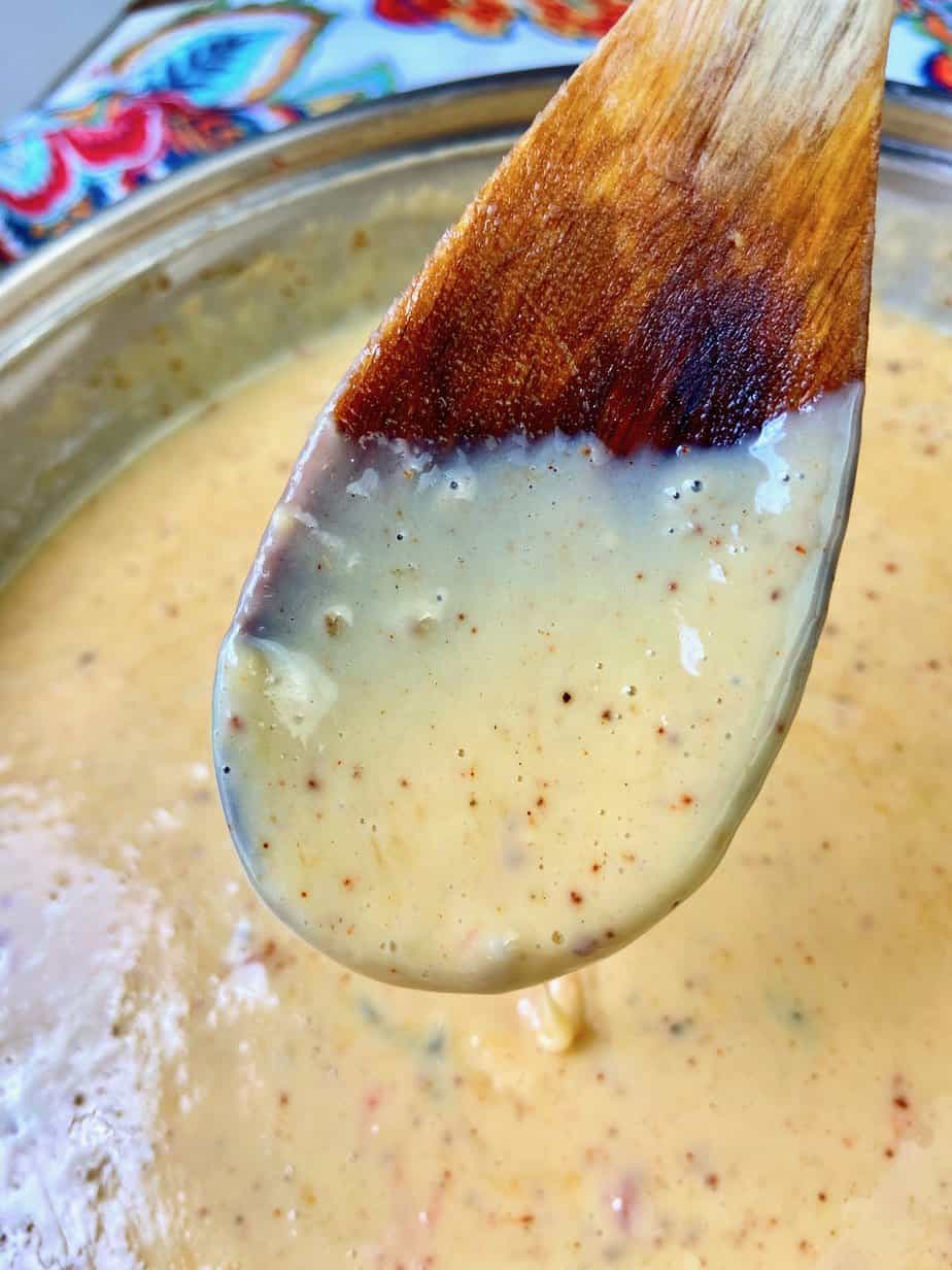 Chile con queso dripping off a wooden spoon.