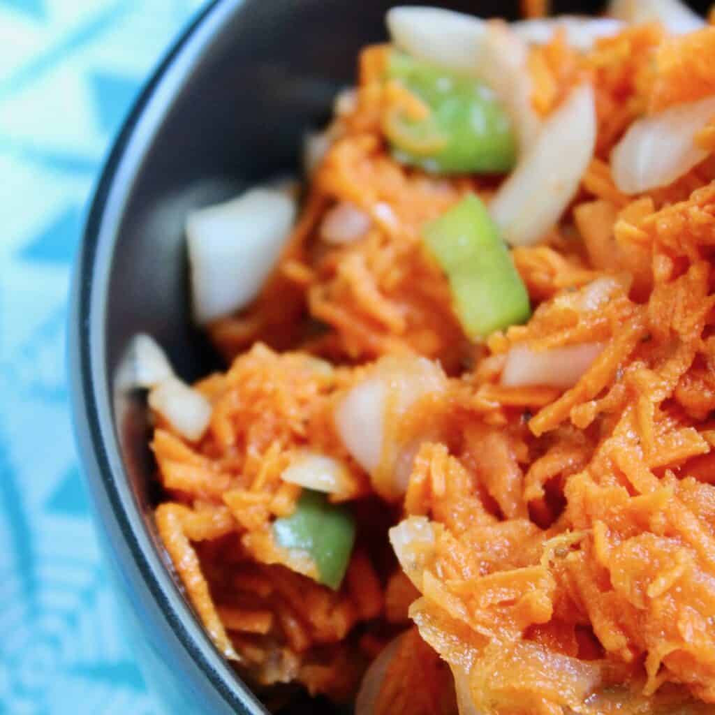 Copper Penny shredded carrot slaw in black bowl.