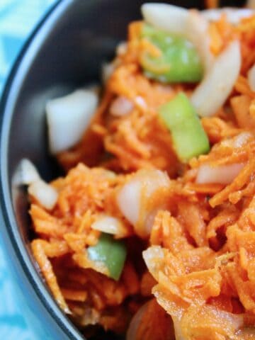 Copper Penny shredded carrot slaw in black bowl.