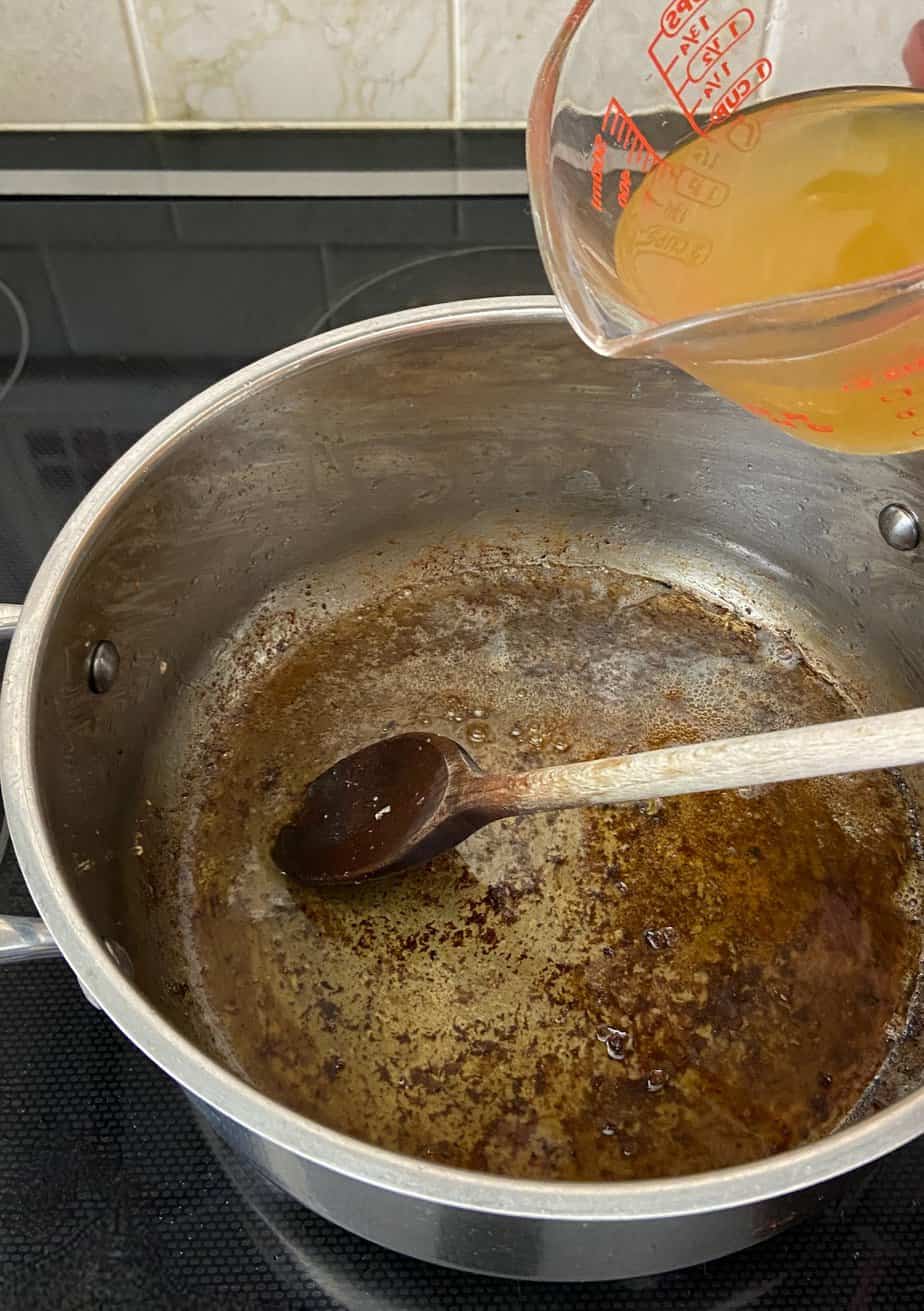 Chicken broth being poured into pot.