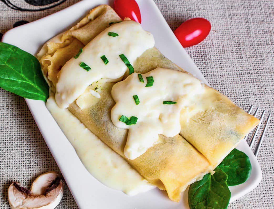 Sausage crepes on white platter.