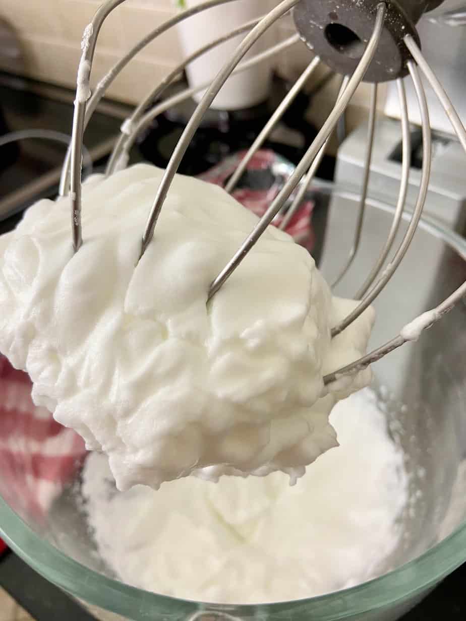 Whipped egg whites at soft peaks on wire whisk.