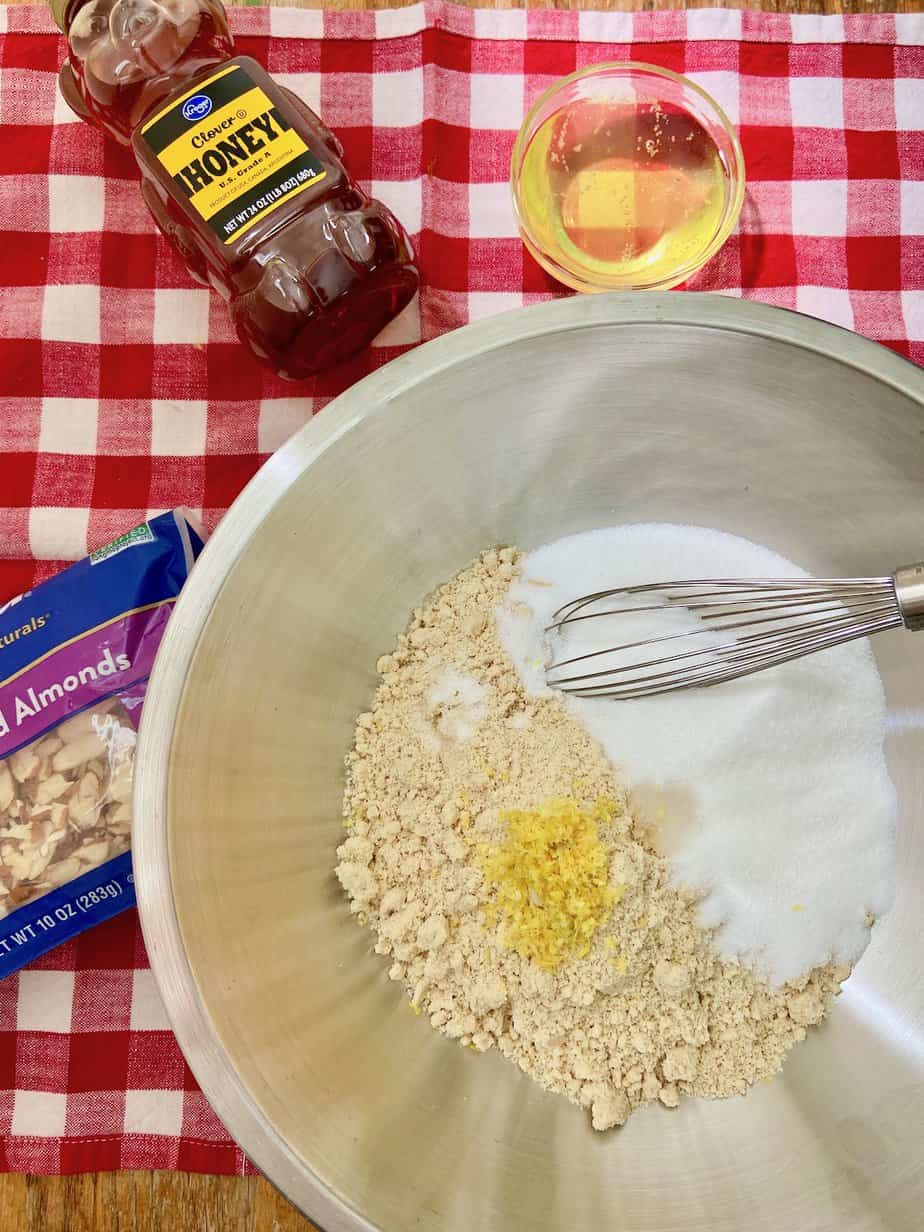 Almond flour, sugar, salt and almond extract in stainless steel mixing bowl.