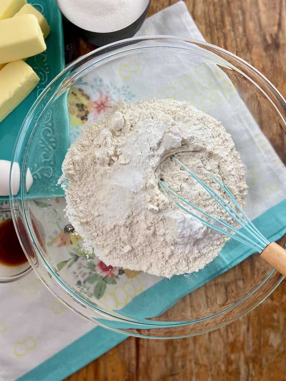 Cookie dough ingredients, Flour, baking powder, baking soda and salt in clear mixing bowl.