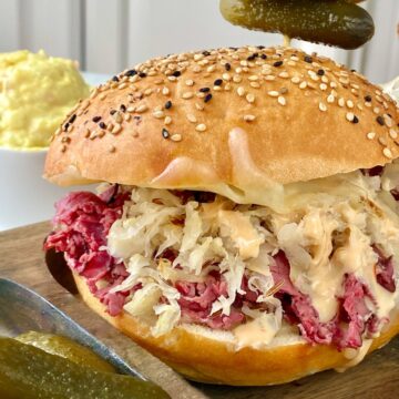 Hot pastrami sandwich on wooden plate.