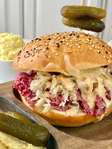 Hot pastrami sandwich on wooden plate.