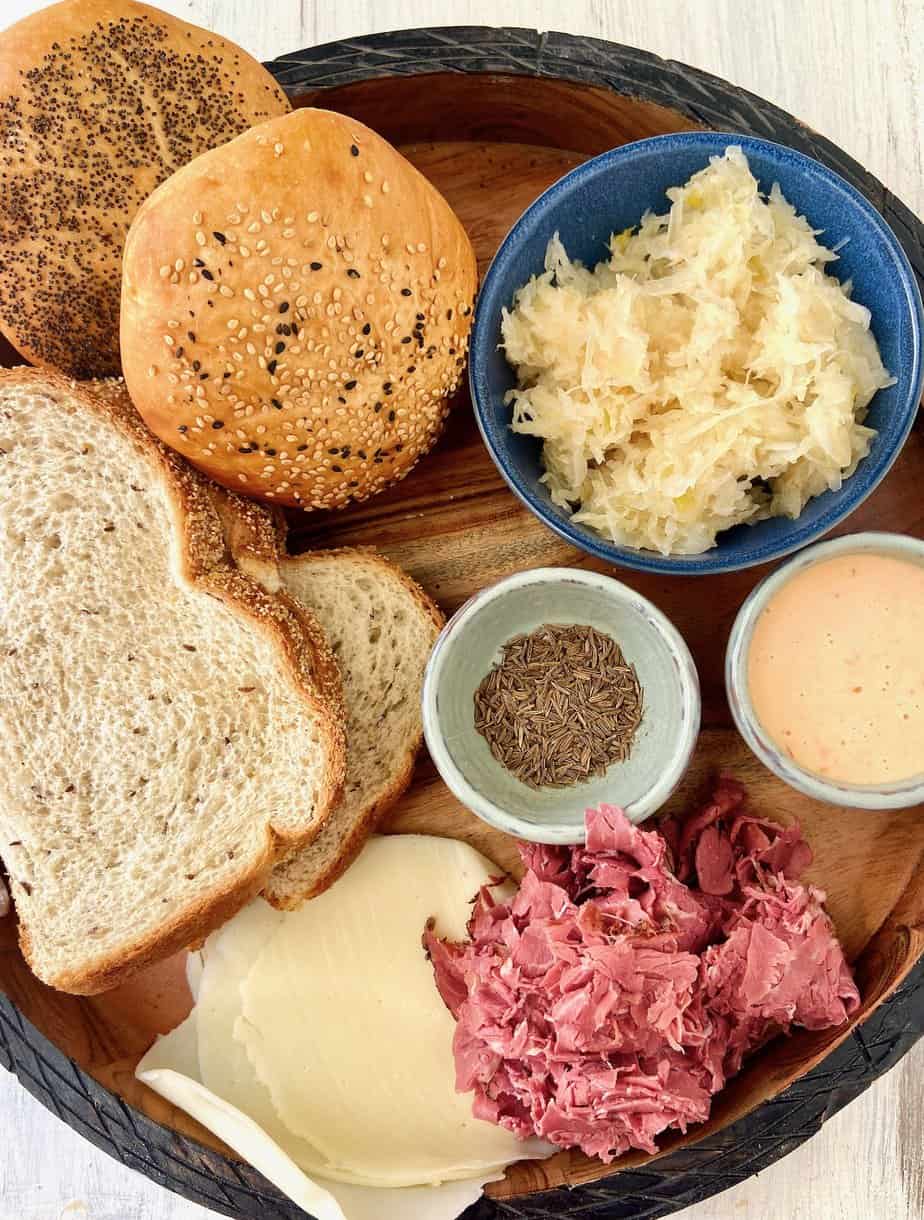 Ingredients for Hot Pastrami Sandwich on round wooden tray.