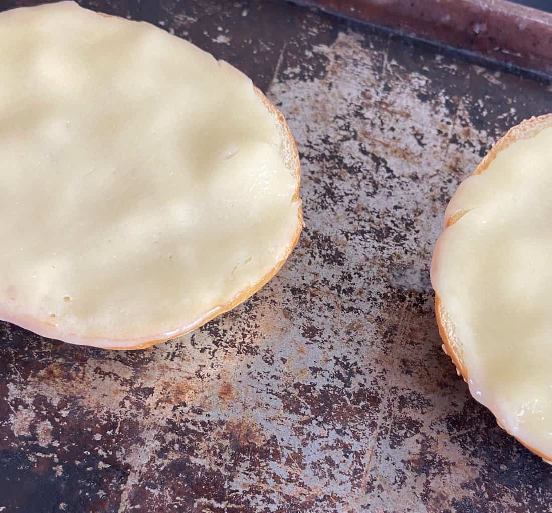 Melted provolone cheese on round bread buns.