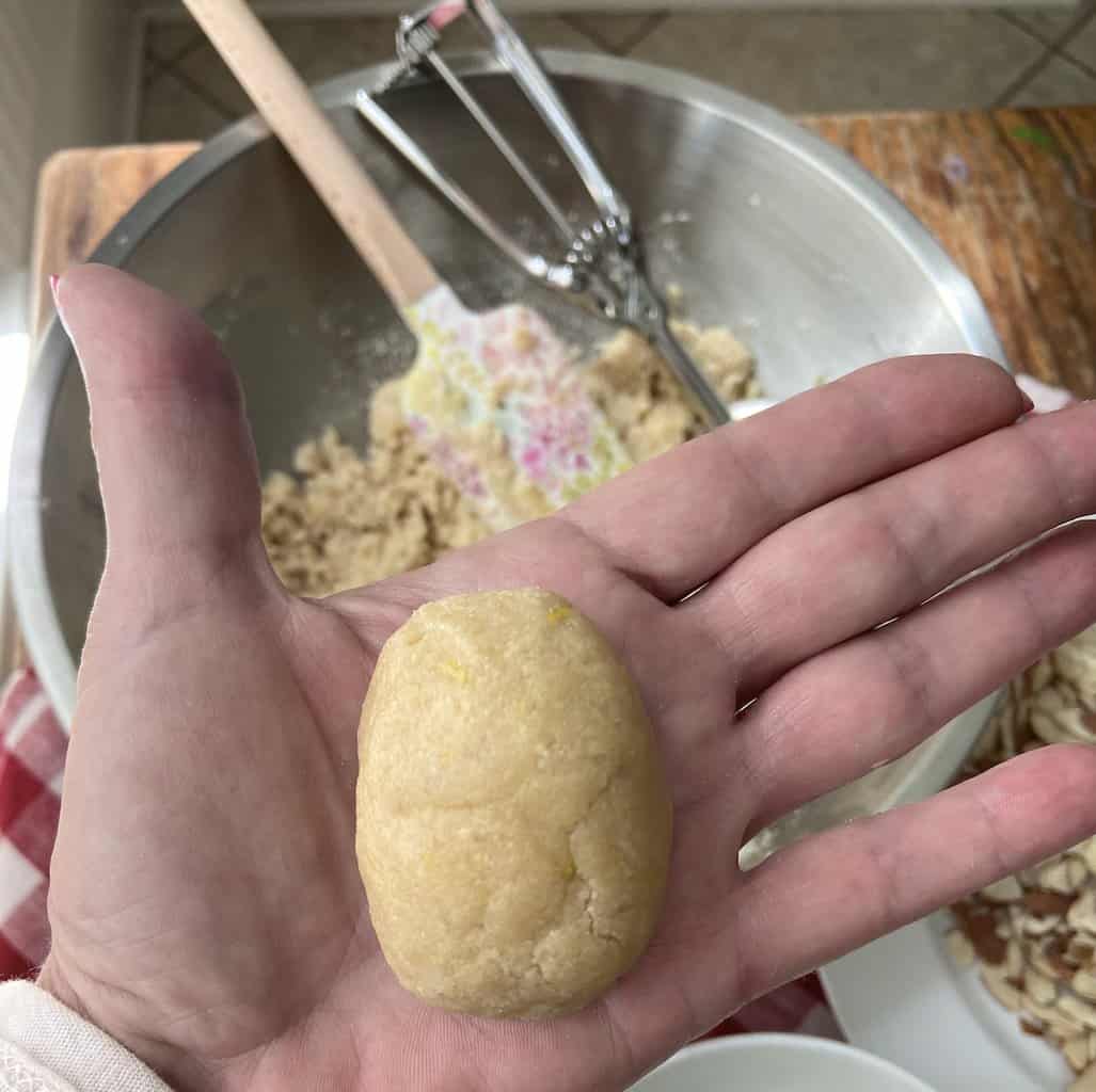 Dough in the shape of an egg in the palm of a hand.