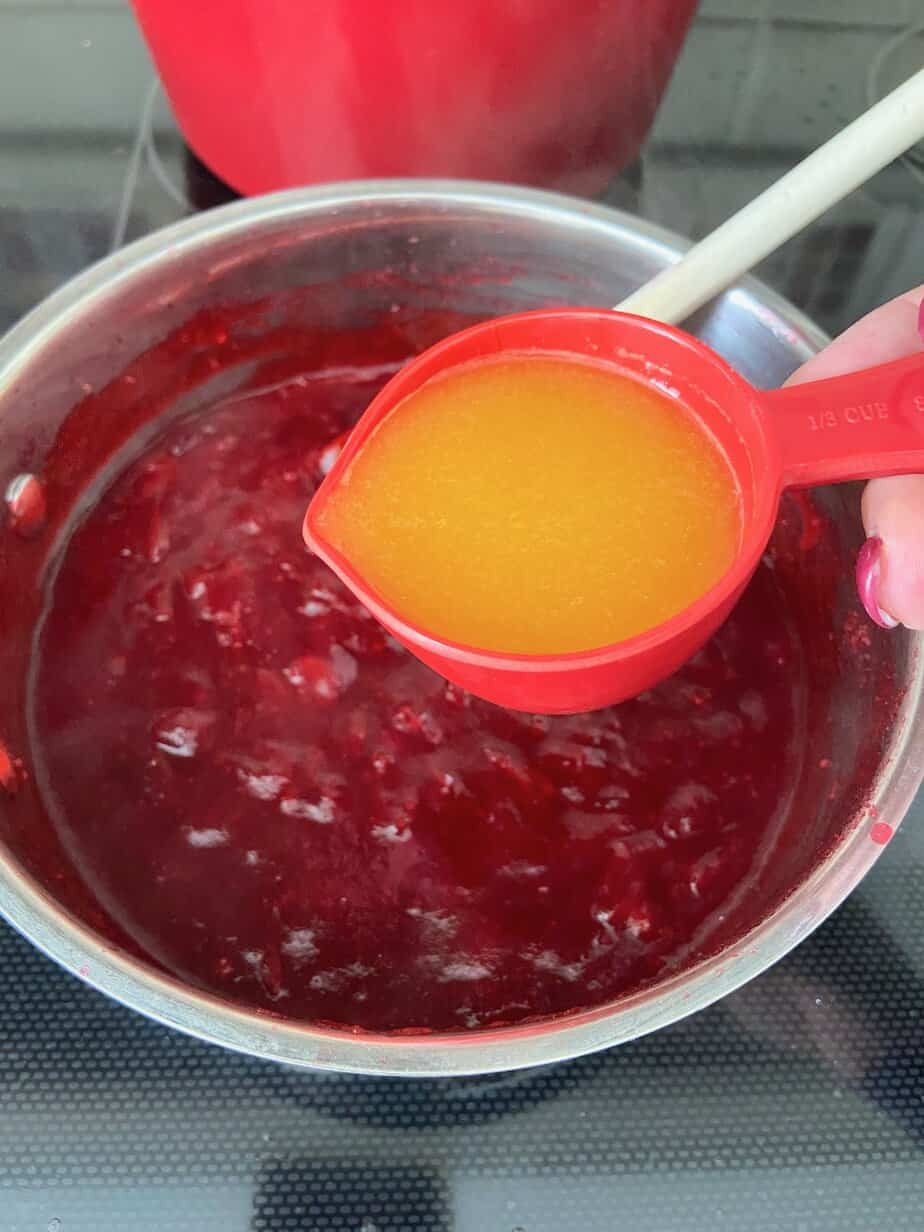 Orange juice being added to saucepan.