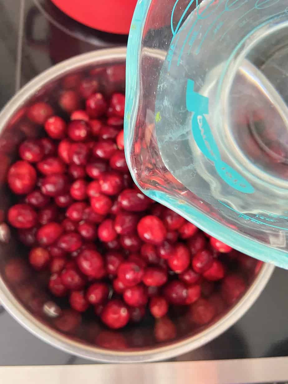 Water being added to cranberries in saucepan.
