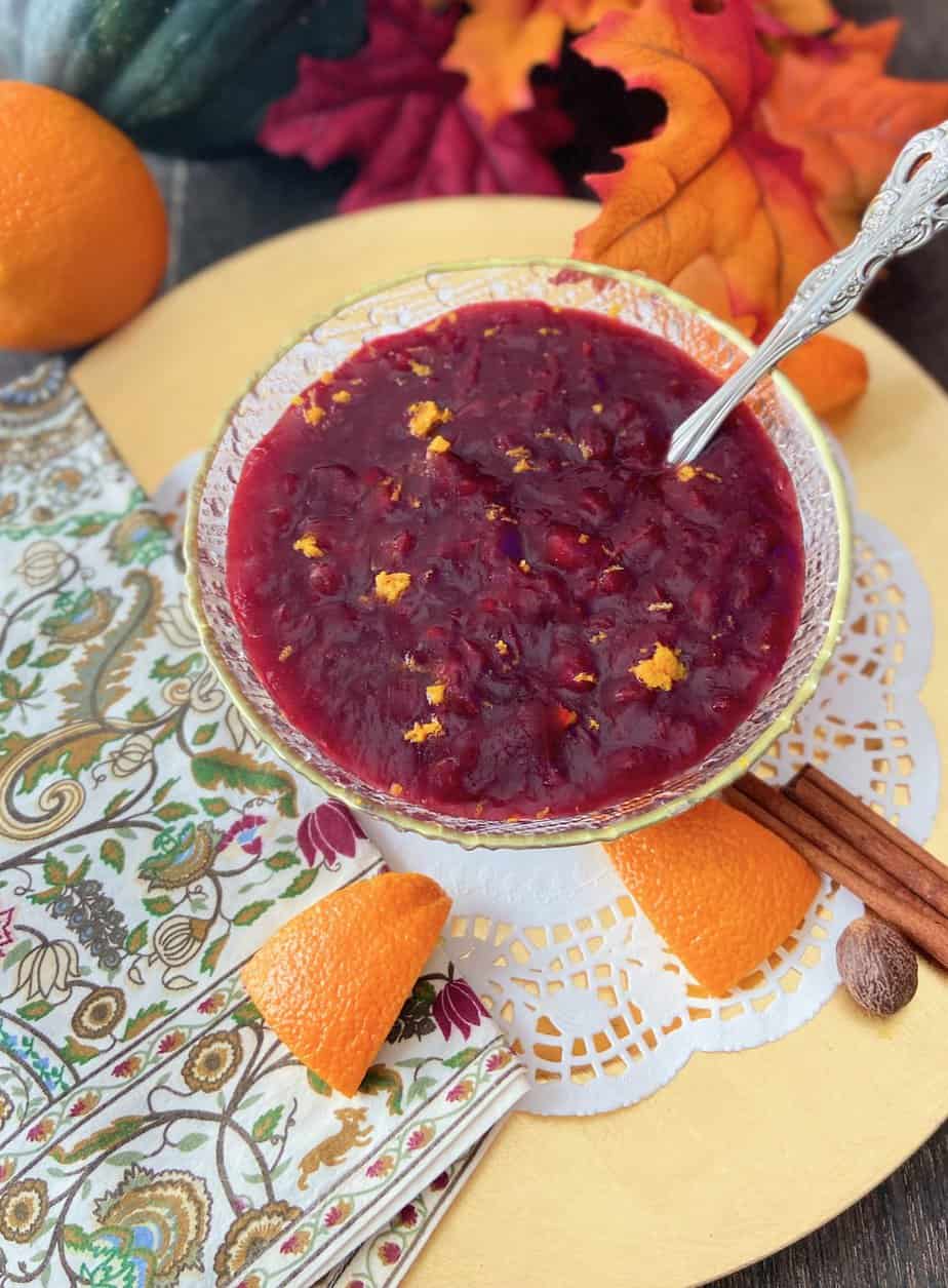 Cranberry sauce in gold rimmed bowl garnished with orange zest.