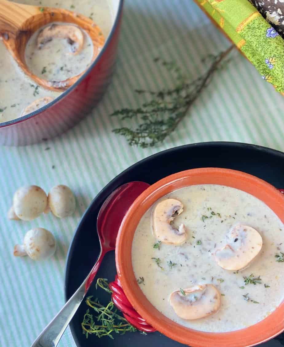 Cream of mushroom soup next to bowl of soup with wooden ladle.