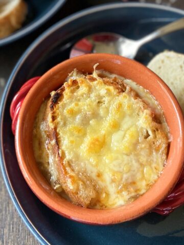 French onion soup in a red bowl.