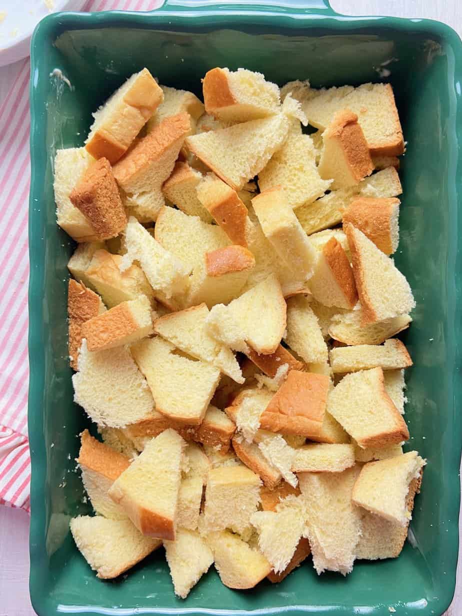 Dried bread cubes in green buttered baking dish.