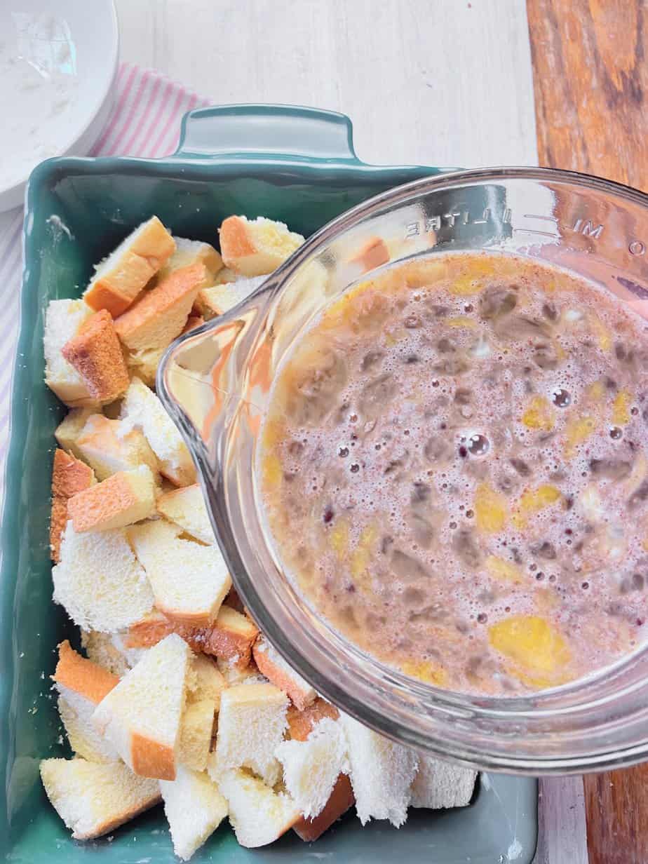 Milk and egg mixture being poured over bread in green pan.