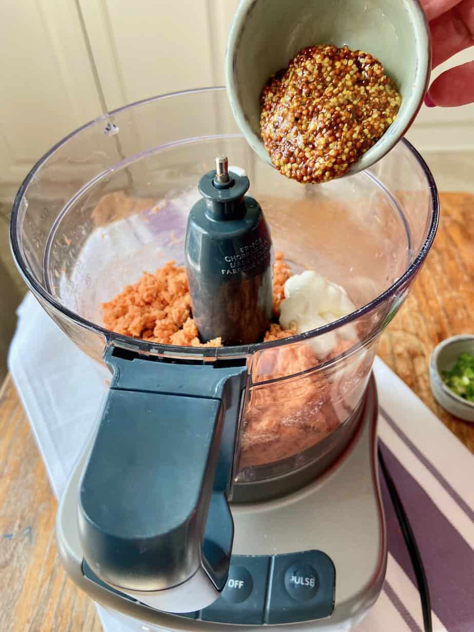 Whole-grain mustard being added to food processor.