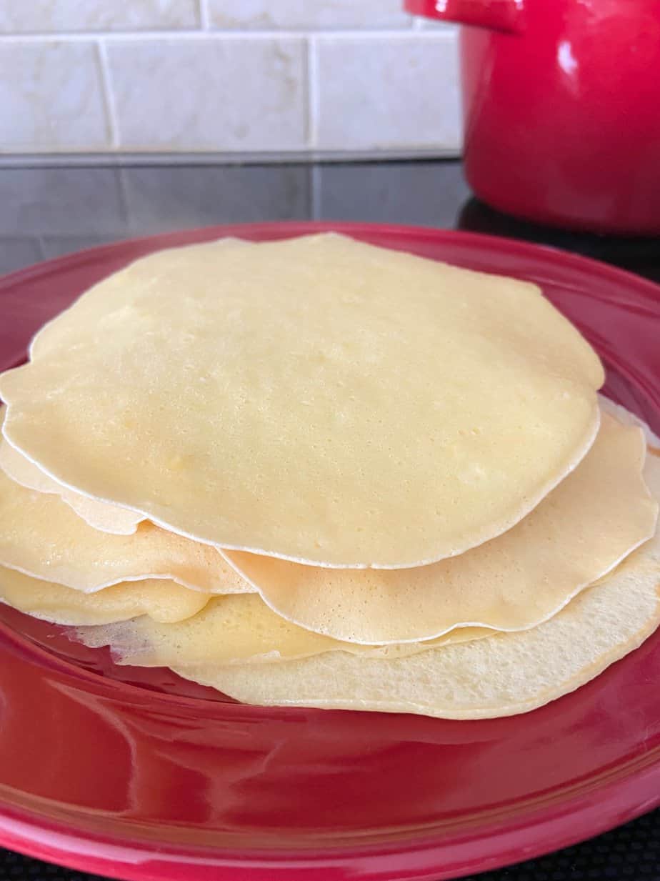 Crepes stacked on a red plate.