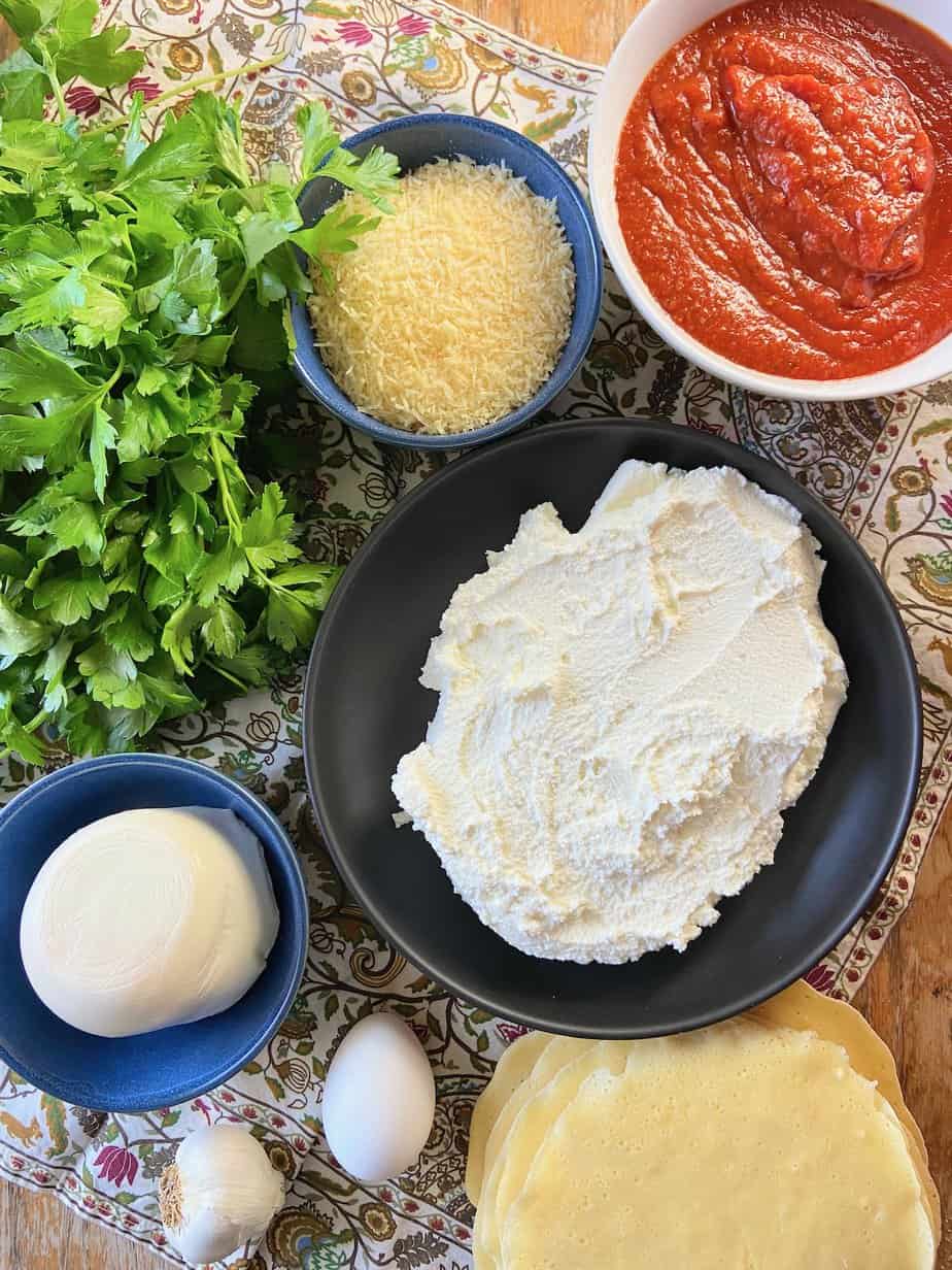 Ingredients for manicotti crepes on wooden table.