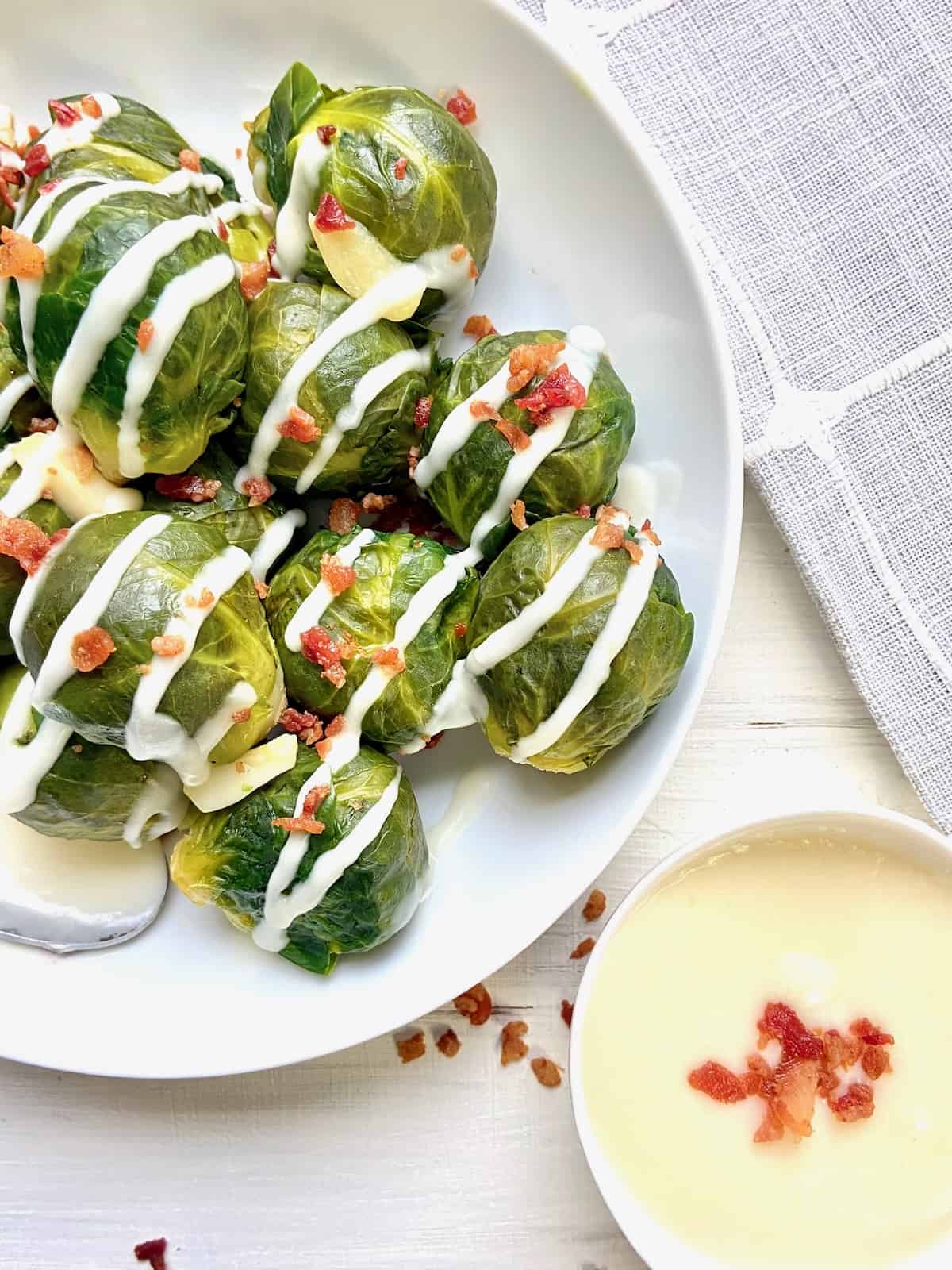 Steamed brussels sprouts garnished with bacon bits and horseradish cream sauce.