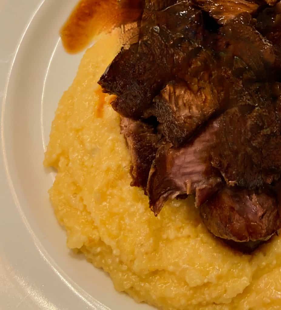 Braised short ribs and cheese grits on plate.