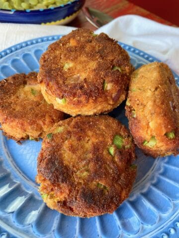 Salmon patties stacked on blue plate.