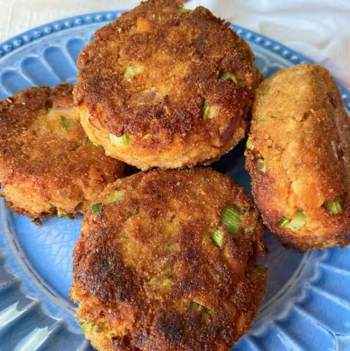 Salmon patties stacked on blue plate.