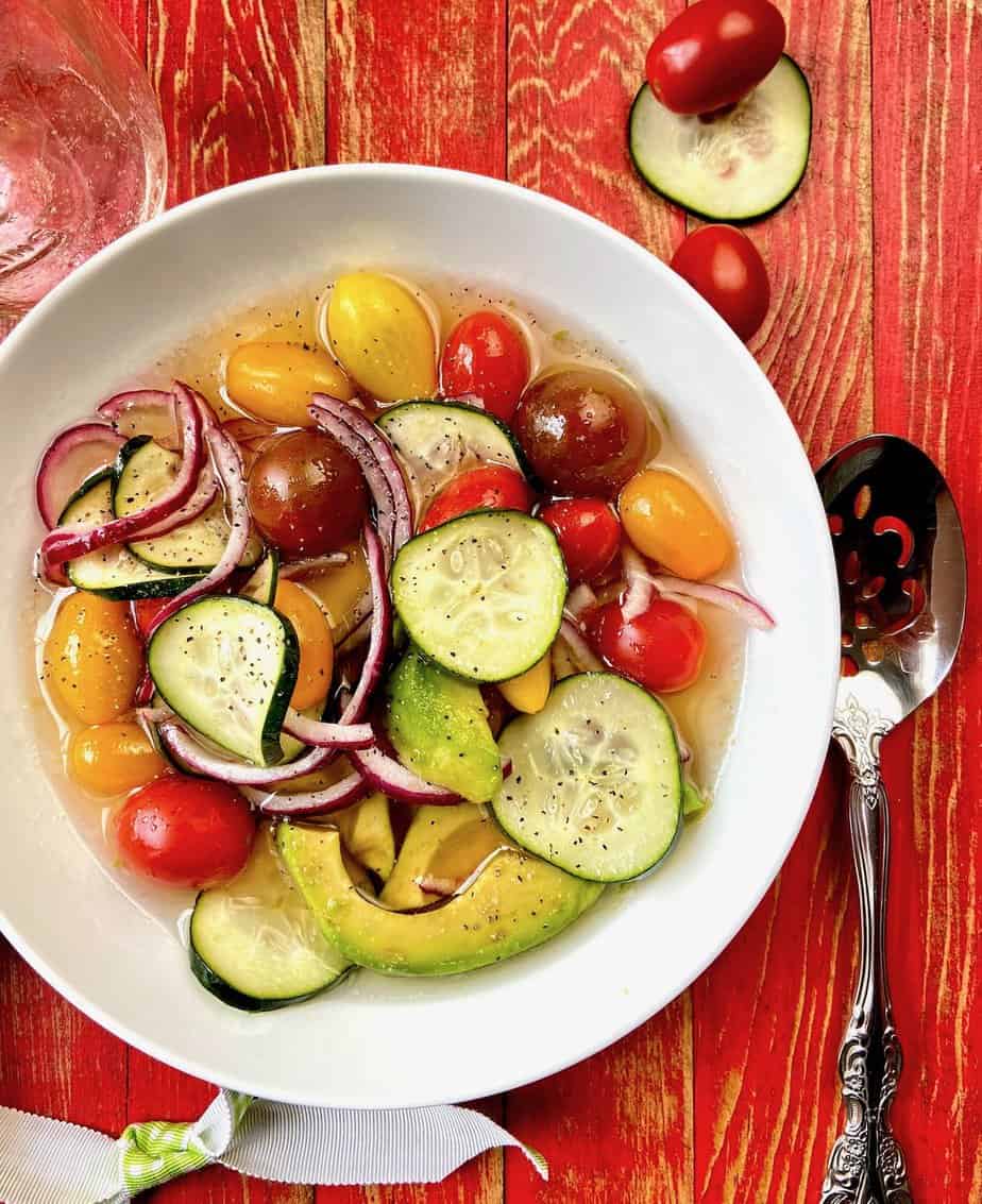 Marinated cucumber tomato salad in white bowl.
