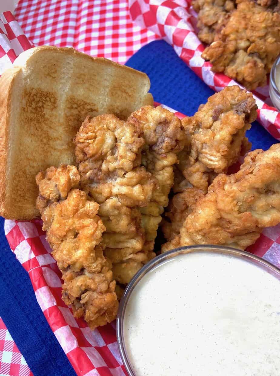 Homemade Dairy Queen Steak Fingers in basket with a side of cream gravy.