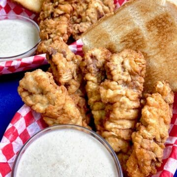 Dairy Queen crispy steak fingers in a red checkered basket with a side of white cream gravy.