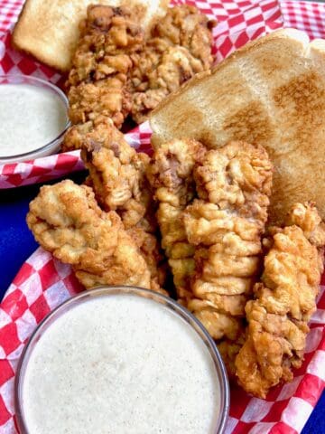 Dairy Queen crispy steak fingers in a red checkered basket with a side of white cream gravy.