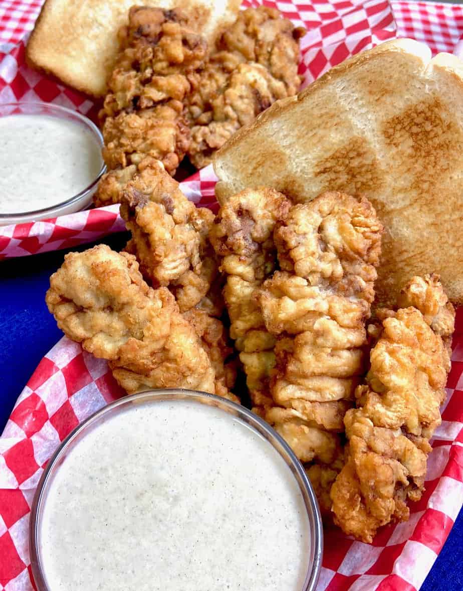 Dairy Queen crispy steak fingers in a red checkered basket with a side of white cream gravy.