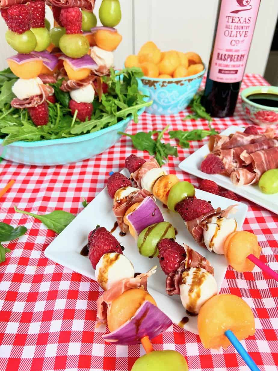 Fruit shish kabobs on white platter.