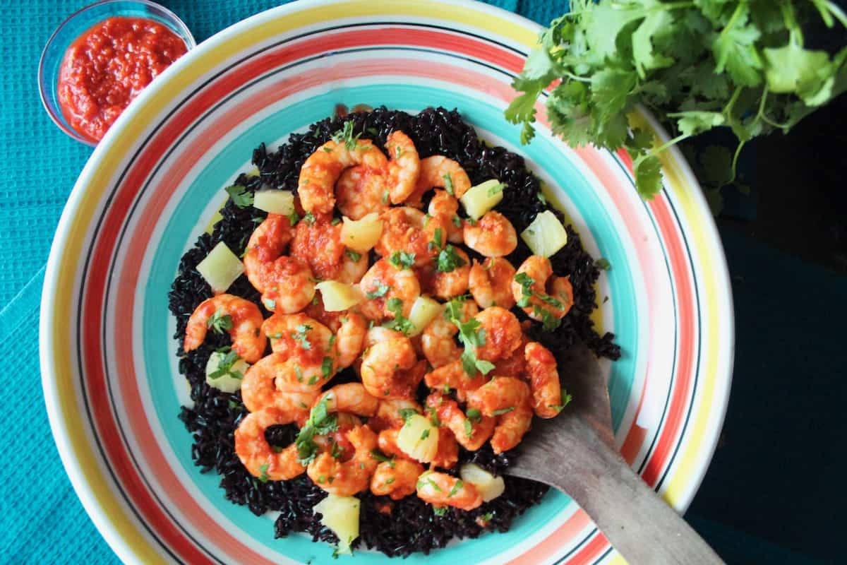 Harissa shrimp and black rice in bowl garnished with cilantro.