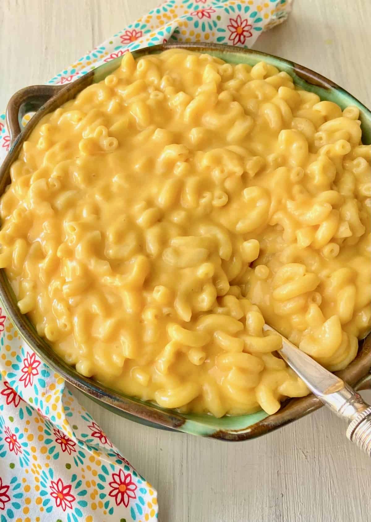 Macaroni and Cheese in green bowl with serving spoon.