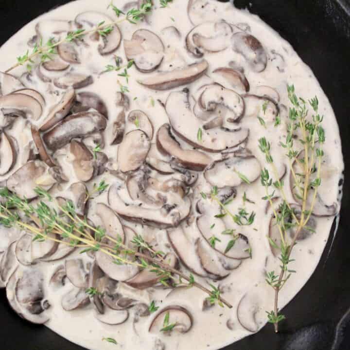 Creamy mushroom sauce in saucepan with fresh thyme sprigs.