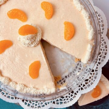 Orange Creamsicle Icebox pie on glass plate with a slice cut out.