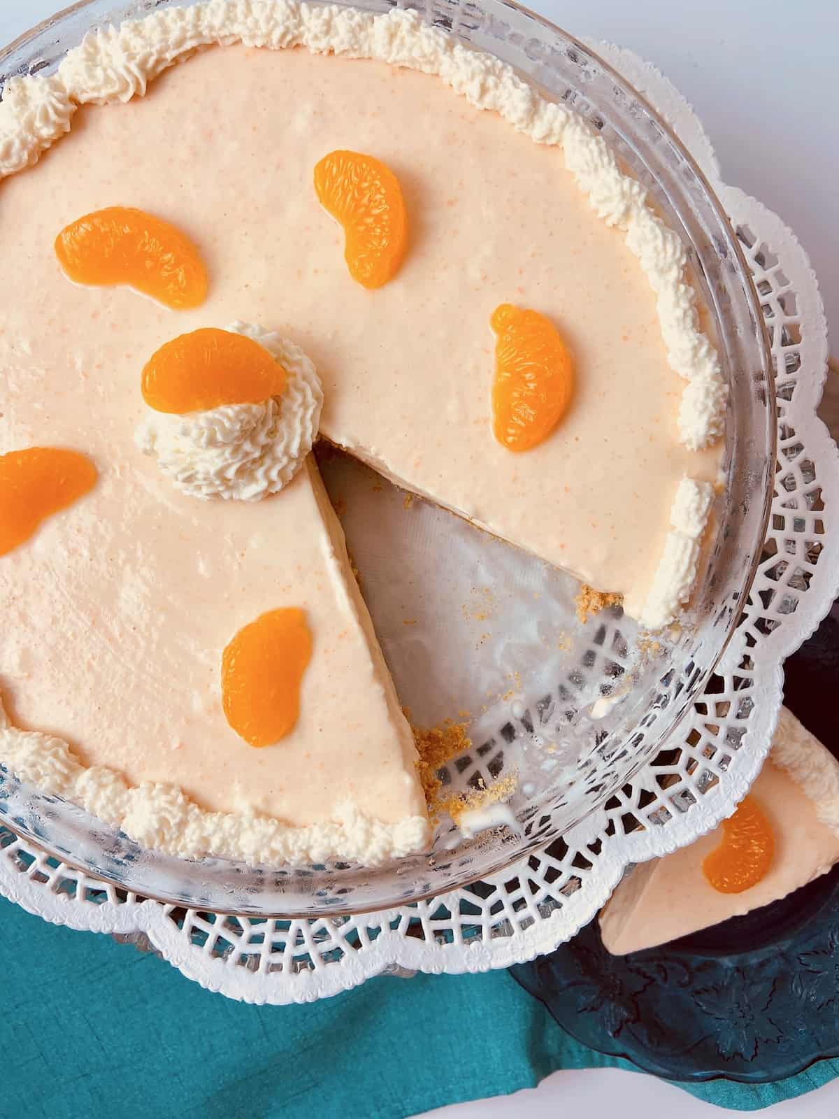 Orange Creamsicle Icebox pie on glass plate with a slice cut out.