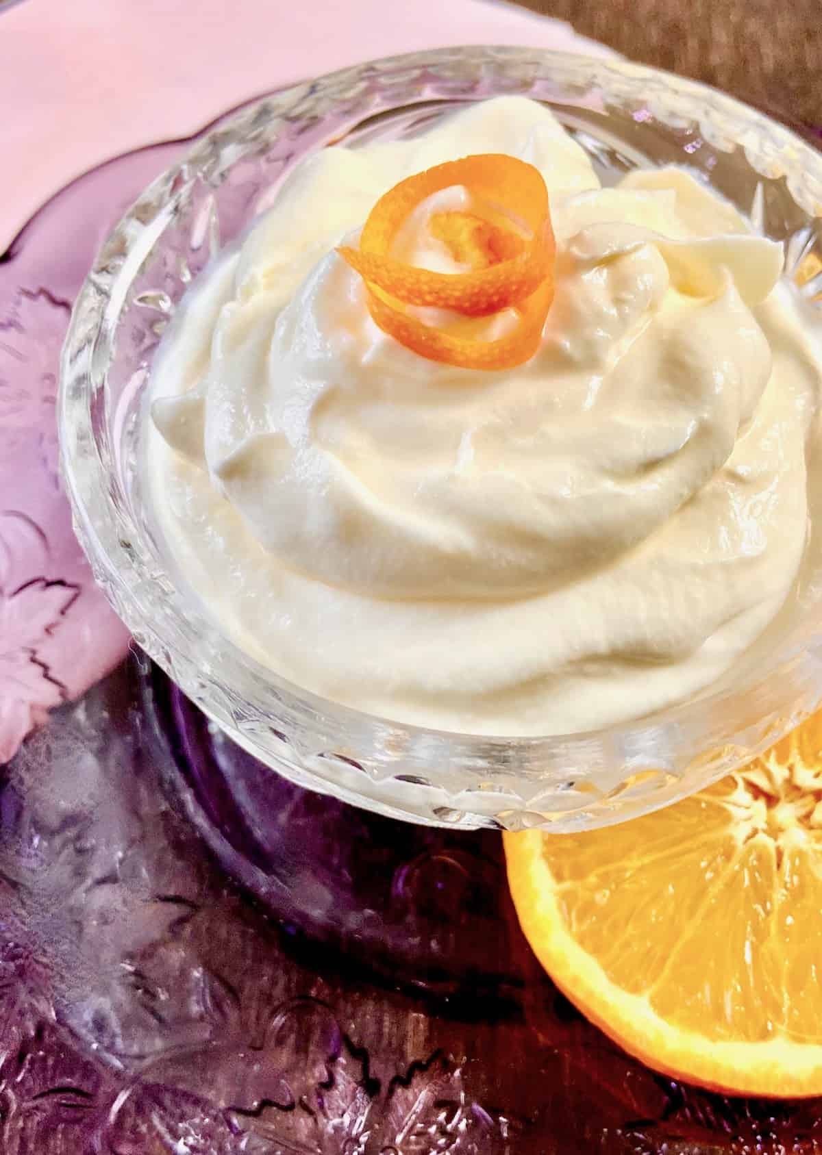 Creme fraiche in crystal bowl with orange garnish.