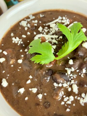 Creamy black bean soup garnished with cilantro and cheese crumbles.
