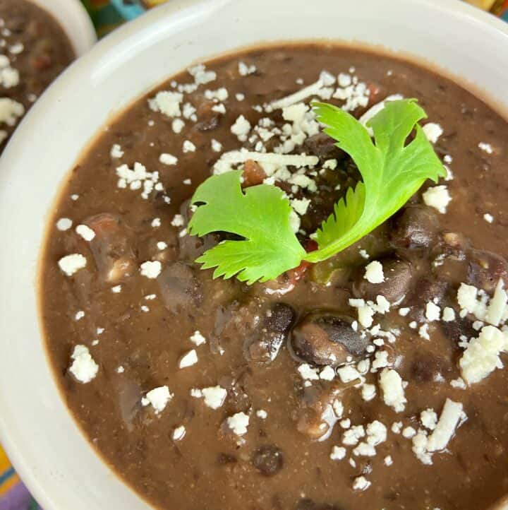 Creamy black bean soup garnished with cilantro and cheese crumbles.