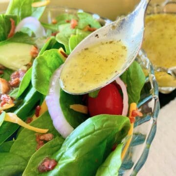 Low sodium salad dressing in spoon drizzling over salad.