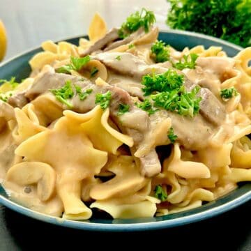 Creamy beef stroganoff nestled in a tangy sour cream sauce garnished with fresh parsley.