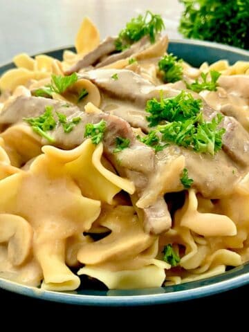 Creamy beef stroganoff nestled in a tangy sour cream sauce garnished with fresh parsley.