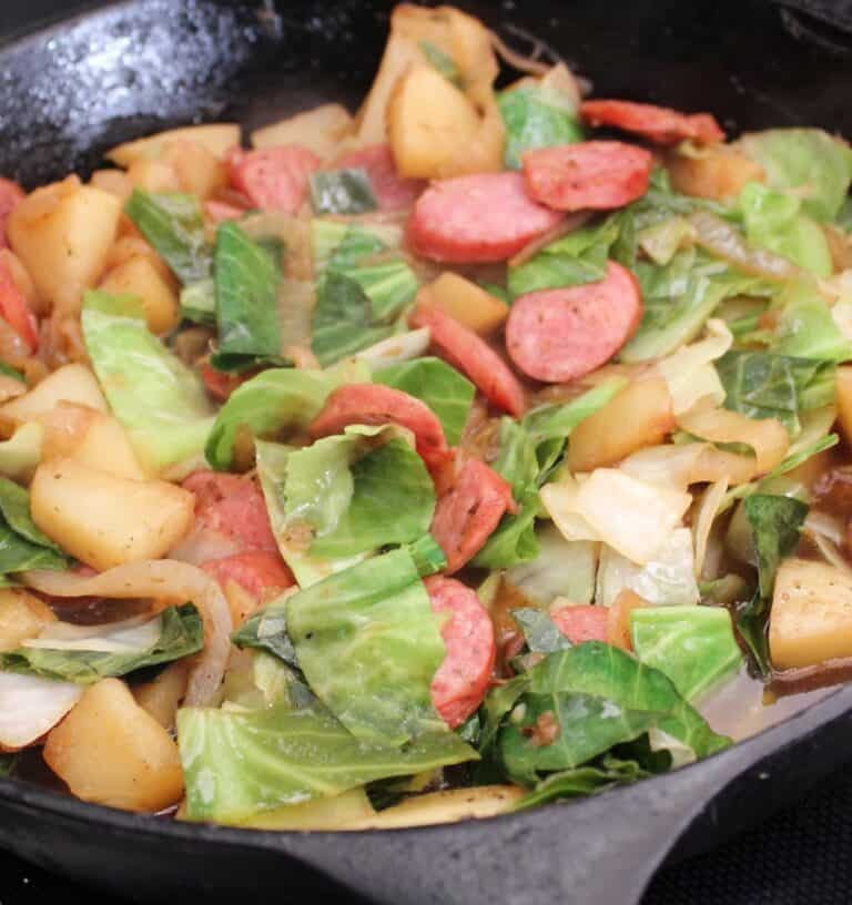 Cabbage, sausage and potatoes in cast iron skillet.