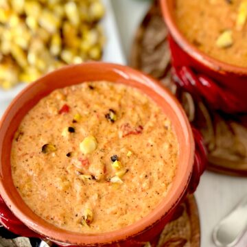 Roasted red pepper corn chowder in red bowl.