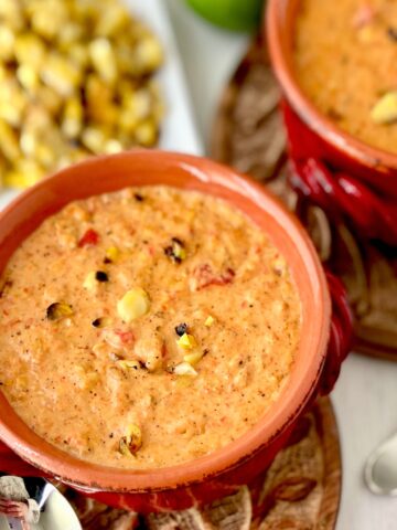Roasted red pepper corn chowder in red bowl.