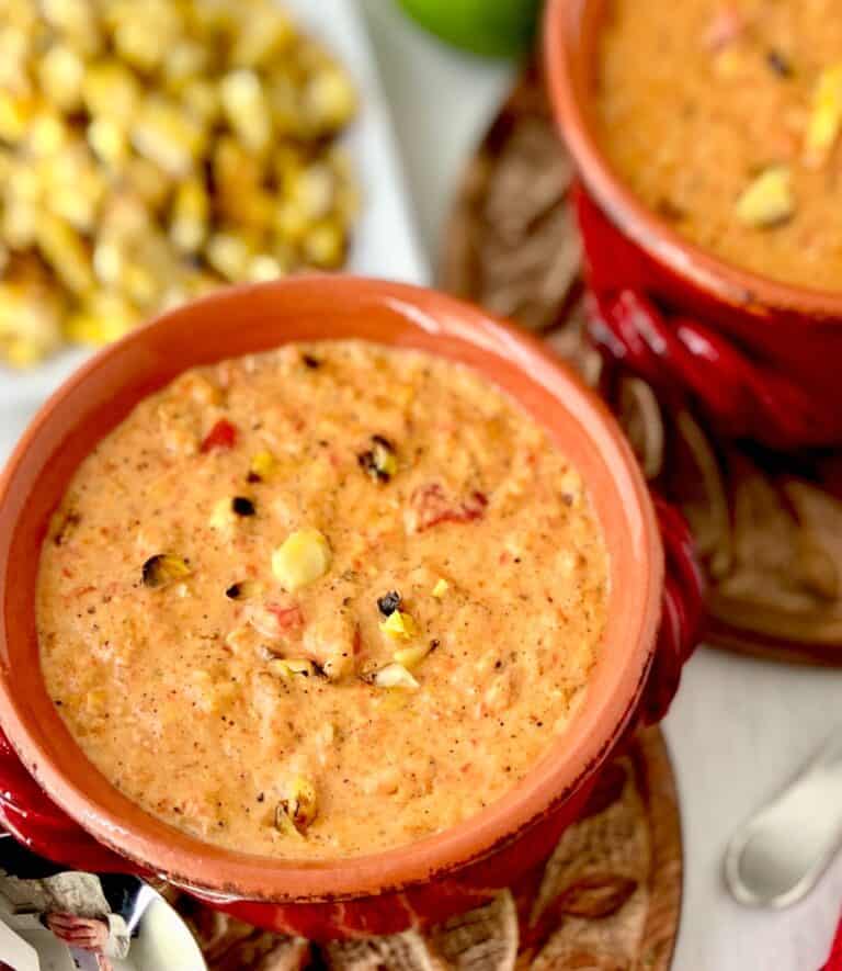 Roasted red pepper corn chowder in red bowl.